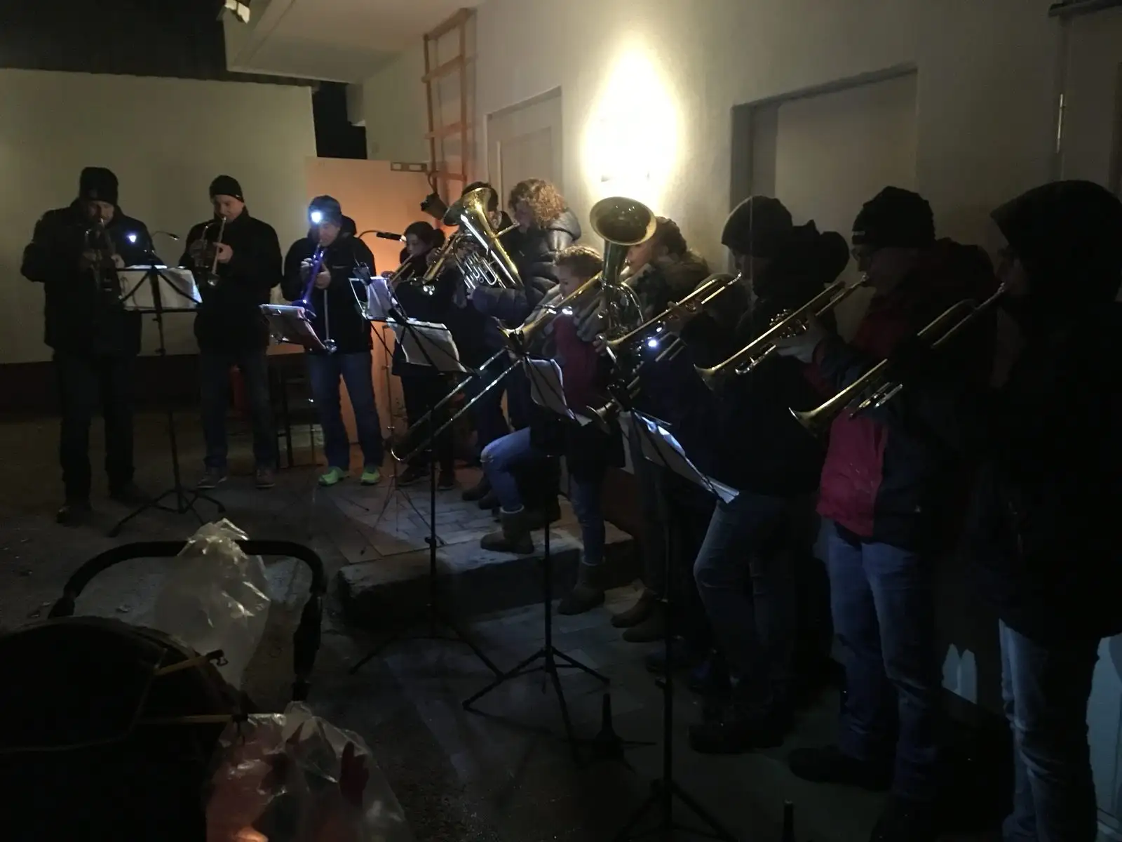 Der Posaunenchor spielt im Halbdunkel mit Trompeten, Posaunen und Tuben, Notenständer mit Stirnlampen beleuchtet