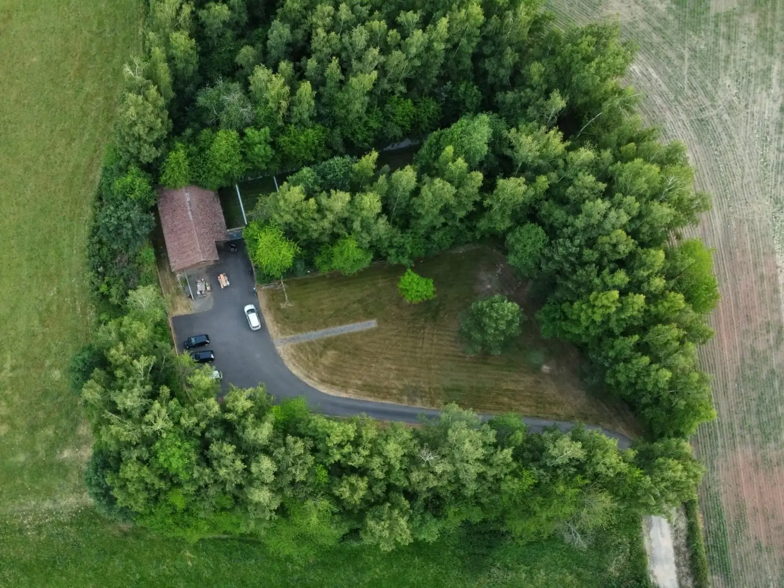 Das Schützenhaus aus der Luft, umgeben von Bäumen, mit Zufahrt und Parkplatz